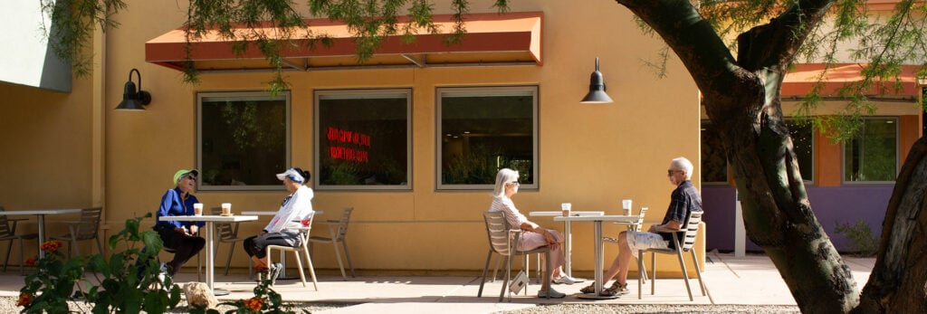 Seniors sitting outside of Posada Java at tables drinking coffee.