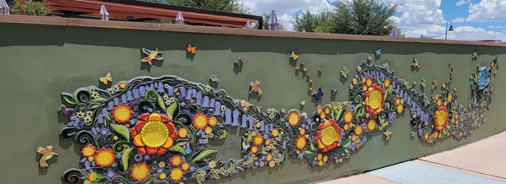 Green wall with a beautiful floral design embossed onto it.